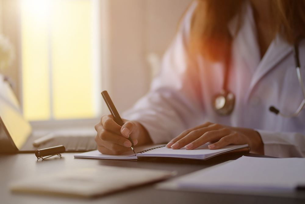 Young female doctor writing medical charts